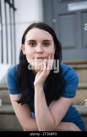 Giovane donna sorridente seduta su gradini Foto Stock