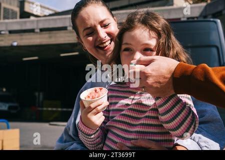 Una famiglia allegra che si gode il gelato insieme nelle giornate di sole Foto Stock