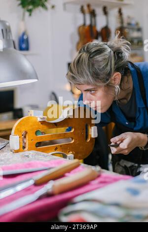 Liutaio che lavora al violino in un laboratorio di strumenti musicali Foto Stock