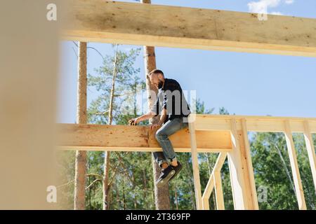 Ingegnere seduto su una cornice di legno nelle giornate di sole Foto Stock