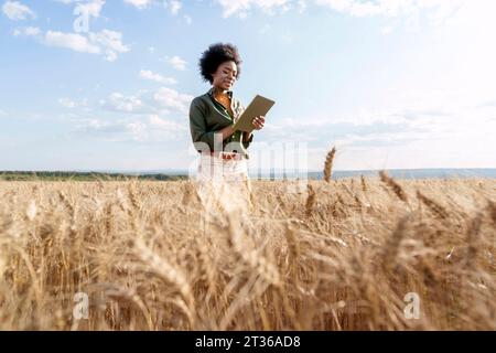 Giovane agricoltore afro che utilizza un tablet PC in un campo di orzo Foto Stock
