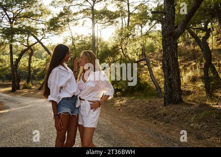 Madre e figlia in piedi faccia a faccia nella foresta al tramonto Foto Stock