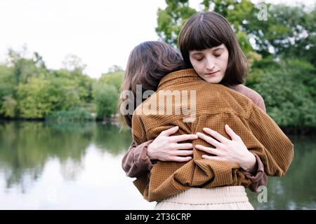 Amate le sorelle gemelle che si abbracciano vicino al lago Foto Stock