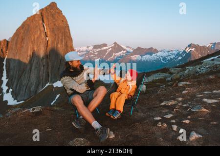Padre e figlia con la famiglia che giocano a cinque mani in giro per le montagne norvegesi papà con la figlia che fa trekking insieme seduti in sedia da campeggio Foto Stock