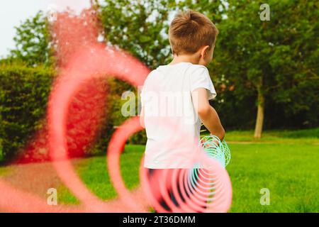 Ragazzo che gioca con il giocattolo primaverile al parco Foto Stock