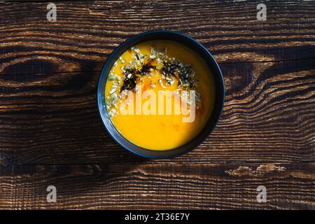 Ciotola con zuppa di zucca vegan su un tavolo di legno, direttamente sopra, autunno sano cibo vegetariano, vista dall'alto Foto Stock