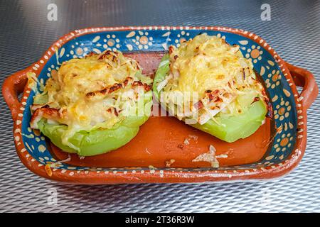 Due fette di chayote ripiene di prosciutto e gratin con formaggio in un vassoio di argilla sul tavolo, verdure coltivate con il metodo biologico. Concetto di originale fatta in casa reci Foto Stock