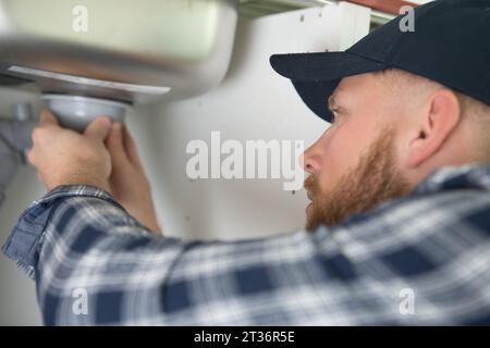 uomo che fissa sotto il lavandino Foto Stock