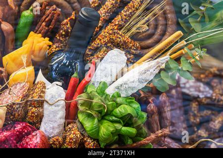 Vetrina gastronomica di specialità gastronomiche sul mercato, assortimento di salsicce e prodotti a base di carne, formaggio, frutta, vino Foto Stock