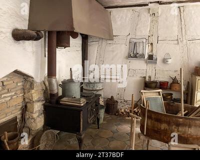 Storica sala di servizio con cucina, fornello sinistro, fornello in ghisa con grande pentola sopra di essa, canna fumaria per camino, vecchio cofano estrattore, vasca destra con Foto Stock