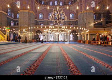 Persone che pregano all'interno della Moschea Blu del XVII secolo illuminata, una storica moschea imperiale dell'epoca ottomana situata a Istanbul, Turchia Foto Stock