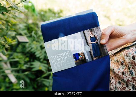 Parigi, Francia - 6 giugno 2023: Un primo piano di una borsa Tchibo per esterni confezionata con una mano che la tiene, collocata sullo sfondo di un giardino Foto Stock