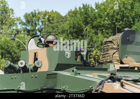 16.08.2023 Varsavia, Polonia. Il portello del caricatore in un carro armato militare. Ritratto all'aperto di un soldato concentrato che sbircia fuori dal carro armato dipinto con camuffamento. Foto di alta qualità Foto Stock