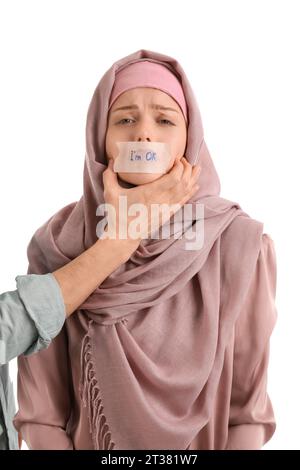 Donna musulmana livisa che tiene carta con testo i'M FINE e suo marito su  sfondo bianco. Concetto di violenza domestica Foto stock - Alamy