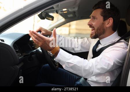 Autista stressato che urla nella sua auto. Bloccato in un ingorgo stradale Foto Stock