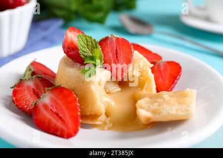 Saporita fondente alla vaniglia con cioccolato bianco e fragole sul tavolo, primo piano Foto Stock