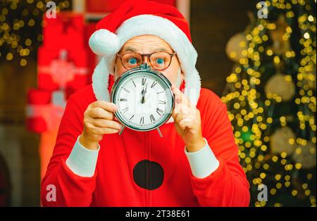 Babbo Natale - barbato e divertente anziano. Foto di Babbo Natale che indica l'orologio da cinque minuti a mezzanotte. Natale. Capodanno e Natale. Foto Stock