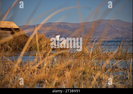 Uros su una barca di canne vicino alla sua isola galleggiante sul lago Titicaca Foto Stock