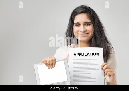 Con i suoi eleganti capelli neri, la signora indiana mostra sia un modulo di applicazione che un tablet, a significare la miscela di metodi tradizionali e moderni. Noi Foto Stock