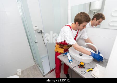 servizio idraulico. Ritratto idraulico vicino all'installazione del sifone del lavabo. Foto Stock