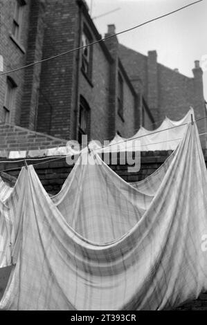 Lavarsi appesi nei cortili posteriori di una strada di case a schiera in attesa di demolizione durante la bonifica dei baraccopoli di St Ann's, Nottingham. 1969-1972 Foto Stock