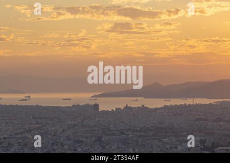 Una vista al tramonto di Atene, presa dal Monte Lycabettus verso il porto e i moli Foto Stock