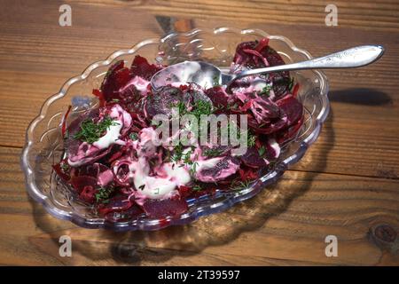 Insalata di barbabietole con aneto e condimento cremoso, sano piatto vegetariano in una ciotola di vetro su un tavolo rustico in legno, fuoco selezionato, stretta profondità di fiel Foto Stock