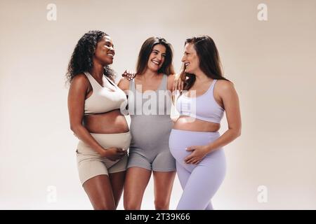 Le mamme che si presenteranno al terzo trimestre partecipano a una diversa lezione di yoga prenatale. Danno la priorità alla cura di sé, supportandosi a vicenda nel loro viaggio per la maternità. Foto Stock