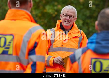 24 ottobre 2023, Brandeburgo, Schönow: Guido Beermann (CDU), ministro dei trasporti del Brandeburgo, scopre il processo compatto di asfalto sulla strada statale L 30 tra Schönow e Gorinsee (Barnim). Questo metodo, in cui vengono applicati contemporaneamente il legante per asfalto e la superficie dell'asfalto, consente di risparmiare tempo ed è anche più duraturo. Foto: Joerg Carstensen/dpa Foto Stock