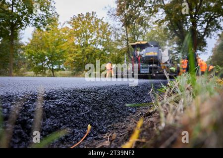 24 ottobre 2023, Brandeburgo, Schönow: La strada statale L 30 tra Schönow e Gorinsee (Barnim) è in fase di rinnovo con il metodo compatto dell'asfalto. Questo metodo, in cui vengono applicati contemporaneamente il legante per asfalto e la superficie dell'asfalto, consente di risparmiare tempo ed è anche più duraturo. Foto: Joerg Carstensen/dpa Foto Stock