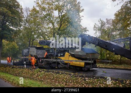 24 ottobre 2023, Brandeburgo, Schönow: La strada statale L 30 tra Schönow e Gorinsee (Barnim) è in fase di rinnovo con il metodo compatto dell'asfalto. Questo metodo, in cui vengono applicati contemporaneamente il legante per asfalto e la superficie dell'asfalto, consente di risparmiare tempo ed è anche più duraturo. Foto: Joerg Carstensen/dpa Foto Stock