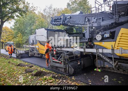 24 ottobre 2023, Brandeburgo, Schönow: La strada statale L 30 tra Schönow e Gorinsee (Barnim) è in fase di rinnovo con il metodo compatto dell'asfalto. Questo metodo, in cui vengono applicati contemporaneamente il legante per asfalto e la superficie dell'asfalto, consente di risparmiare tempo ed è anche più duraturo. Foto: Joerg Carstensen/dpa Foto Stock