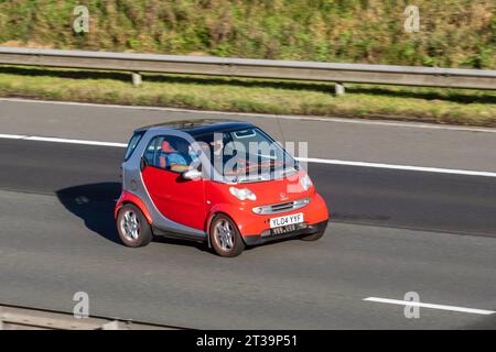 2004 Smart City Passion 61 Auto SofTouch Auto Red Car Coupé benzina 698 cc; viaggia a velocità sostenuta sull'autostrada M6 a Greater Manchester, Regno Unito Foto Stock