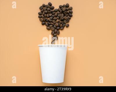 Tazza di carta e chicchi di caffè a forma di cuore. Arte minimalista moderna e alla moda. Foto Stock