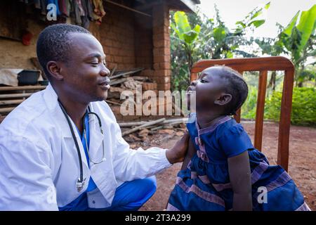 Medico africano che parla con una bambina ammalata durante una visita in una zona rurale in Africa. Foto Stock
