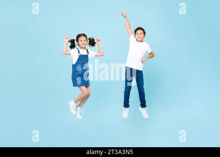 Razza mista ragazzo e ragazza asiatica che giocano saltando in aria su sfondo isolato di colore azzurro Foto Stock