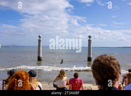 Cais das Colunas in Piazza del commercio con i giovani che si godono il sole pomeridiano sui gradini di marmo del molo vintage di Lisbona, Portogallo Foto Stock