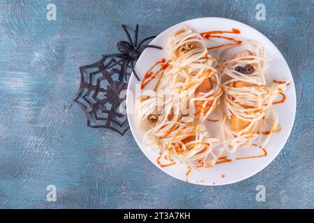 Cibo divertente per bambini per il pranzo o la cena di Halloween. Spaghetti con salsicce, ricetta creativa sotto forma di mummie con ketchup fatto di sangue, con Hallowe Foto Stock