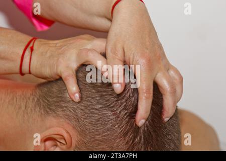 Professional collo terapeutico e massaggio della testa. l'uomo l'atleta in una sala massaggi. dolore la procedura di recupero. Fisioterapista femmina facendo manipolative Foto Stock