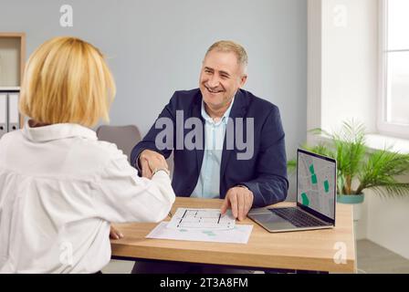 Agente immobiliare che stringe la mano a un cliente che fa un affare di acquisto di una casa o sceglie un terreno. Foto Stock