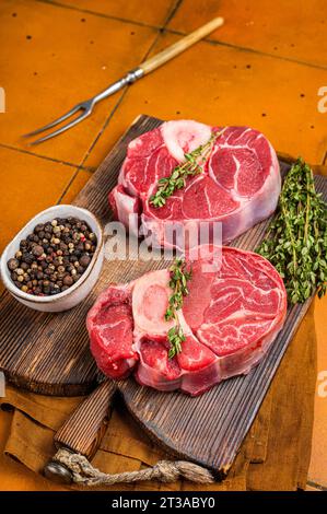 Codolo di vitello osso buco, codolo di vitello crudo tagliato a croce, ossobuco italiano. Sfondo arancione. Vista dall'alto Foto Stock
