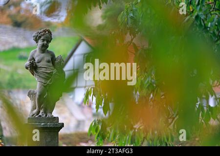 Blankenburg, Germania. 24 ottobre 2023. Le prime foglie sono diventate autunnali intorno a una scultura nel giardino barocco del piccolo castello di Blankenburg. Questo parco è stato costruito intorno al 1725 come giardino principesco. Il parco dispone di quattro terrazze, che invitano i visitatori con fontane, sculture in arenaria, piantagioni, panchine e sentieri. Nei prossimi giorni le condizioni meteorologiche rimarranno variabili. Crediti: Matthias Bein/dpa/Alamy Live News Foto Stock