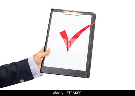 Mano di un uomo d'affari che tiene un appunti con un segno di spunta rosso, isolato su sfondo bianco Foto Stock
