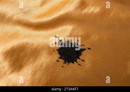 Inchiostro nero rotondo su tessuto satinato arancione dorato, primo piano Foto Stock