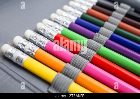 Matite colorate arcobaleno con gomma, disposte in una scatola di matite, sullo sfondo astratto di ritorno a scuola Foto Stock