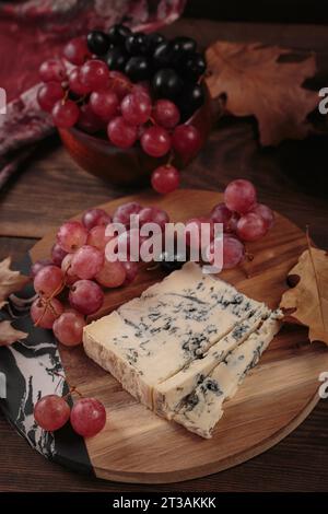 Piatto di formaggi servito con frutta autunnale e foglie secche Foto Stock