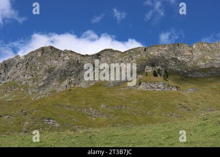 Vista dei verdi pendii di montagna sovrastati da un cielo nuvoloso e blu Foto Stock