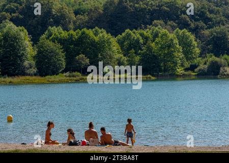 Lago Virieu, Francia - 08 31 2021: Passo Grand Colombier. Vista di una coppia con i loro tre bambini seduti sul bordo dello stagno Foto Stock