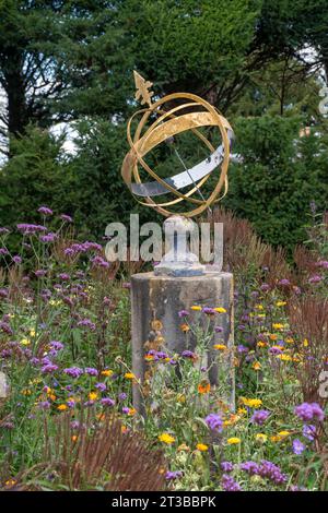 Meridiana a sfera armillare in un giardino circondato da fiori selvatici Foto Stock