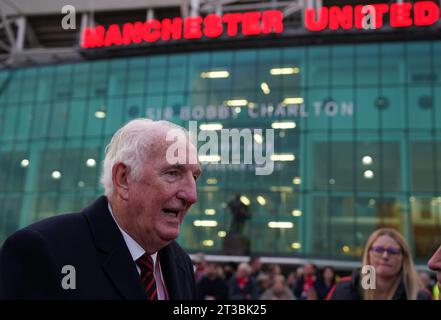 L'ex giocatore del Manchester United Alex Stepney visita i tributi in memoria di Sir Bobby Charlton che si trovano fuori dallo stadio, dopo la sua morte all'età di 86 anni, davanti alla partita di UEFA Champions League tra Manchester United e FC Copenhagen all'Old Trafford, Manchester. Charlton è stato un membro chiave della squadra inglese vittoriosa Coppa del mondo 1966 e ha anche goduto di un grande successo a livello di club con lo United, che è diventato il primo club inglese a vincere la Coppa Europa nel 1968. Data immagine: Martedì 24 ottobre 2023. Foto Stock